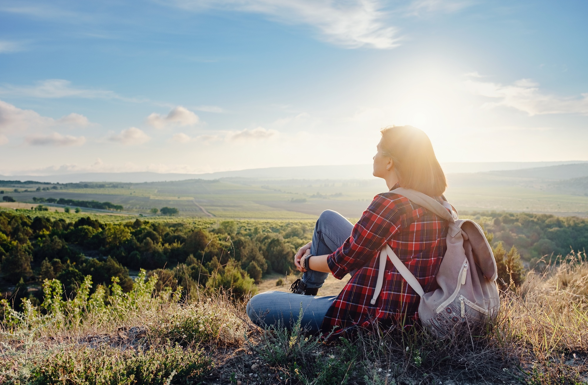 Young hipster girl enjoy sunset on viewpoint. Travel woman with backpack